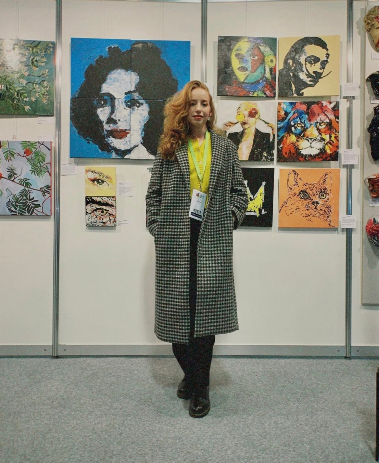 Anastasija Aleksejeva in front of her paintings at an art fair